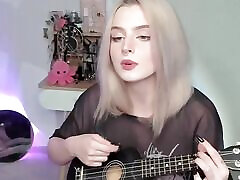Hot blonde girl playing on ukulele and singing in naughty outfit
