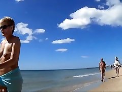 Group of mature nudists walks around the beach naked