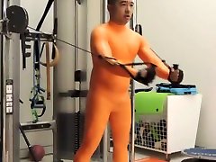 working out in full orange latex suit