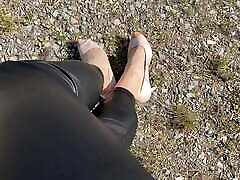 Crossdresser outdoor in shiny coated leggings and heels