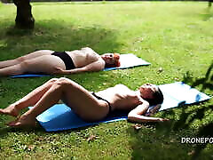 Two piss time girls sunbathing in the city park