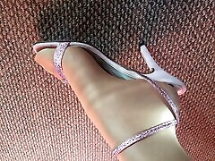 mis pies se ven de cerca en pantimedias brillantes y brillantes y sandalias de tacón rosa sexy