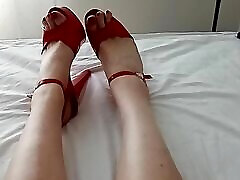 die geile milf-übersetzerin spricht mit ihrer sexy stimme und zeigt ihre rot lackierten zehen in ihren roten lieblings-high-heels