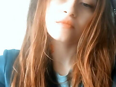Red-haired Asian woman with tattoos blows smoke