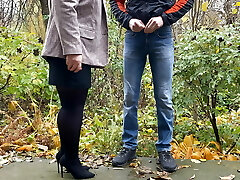 Hot milf in pantyhose and skirt holding dude's fuckpole outdoors while pissing